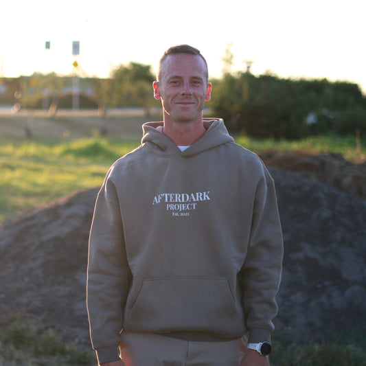 Man wearing AfterDark Project oversized olive hoodie in a casual outdoor setting — streetwear designed by a Canadian brand for fall and winter.